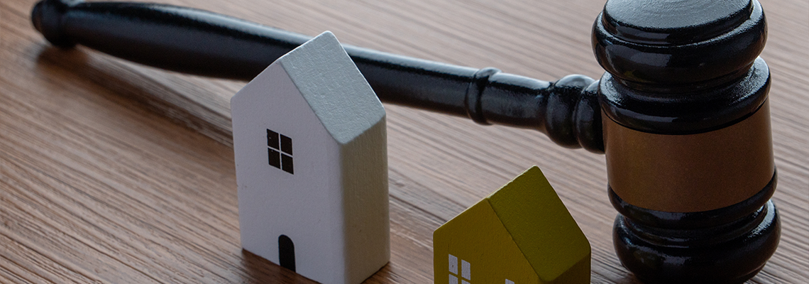A gavel and two miniature wooden houses. Real estate law, property disputes,
