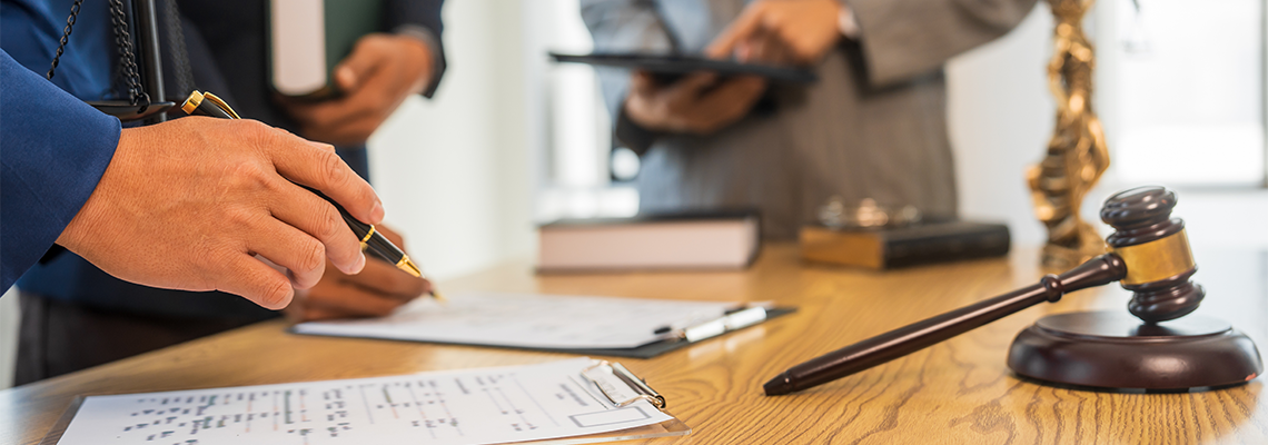 A team meeting of business people and a lawyer in formal suits is taking place at a desk