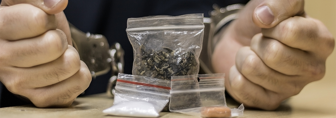 Photo of a Caucasian man, with handcuffs on his wrists for being in possession