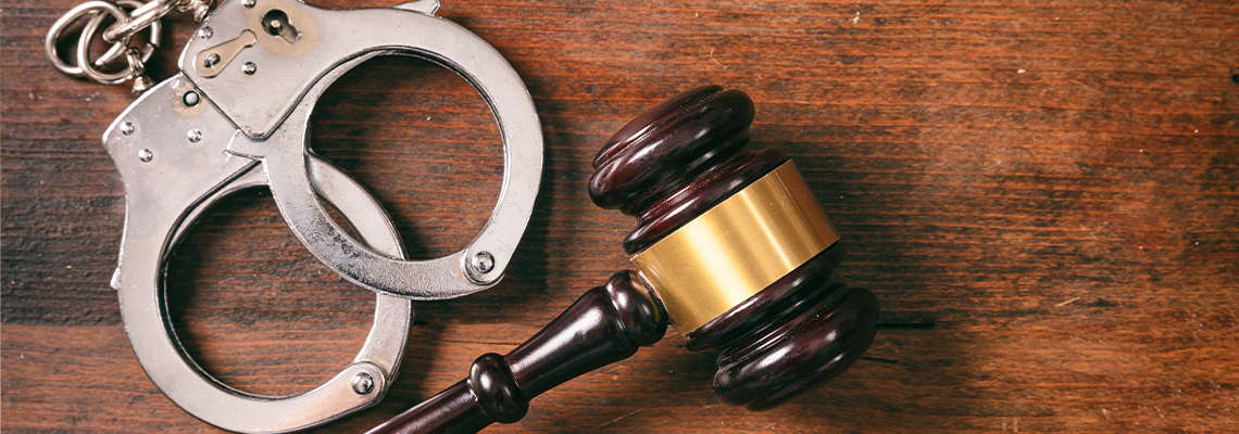 Handcuffs isolated and a gavel with copy space on a wooden background