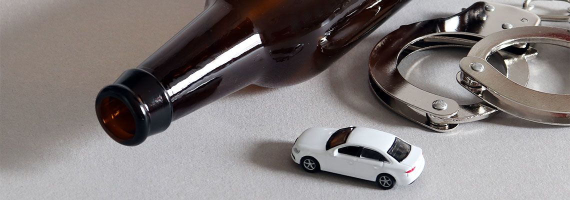 Beer bottle, toy car and handcuff in table