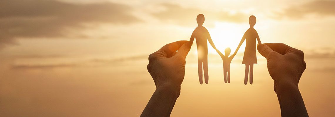 Hands holding Paper cut out of family figures