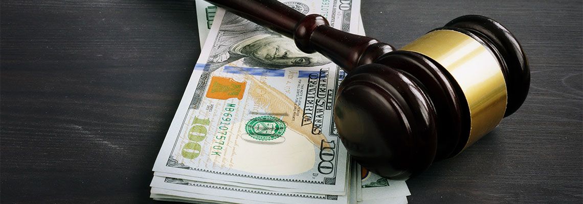 Gavel and money in wooden desk representing legal cost