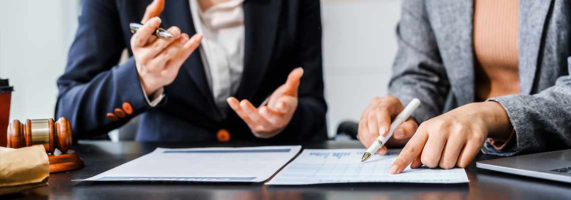 Two female lawyers in business suits meet at wooden desk