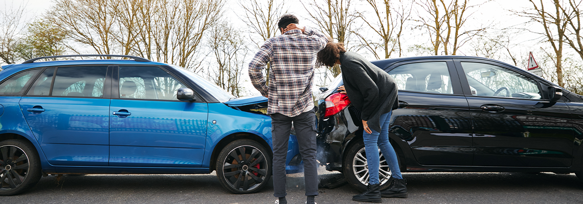 Male And Female Drivers Getting Out Of Cars And Inspecting Damage
