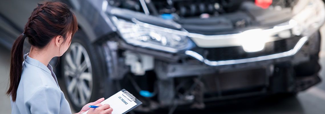 Insurance agent inspecting damages of car after accident