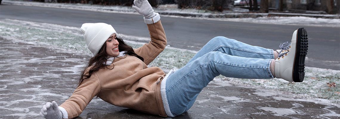 Young woman slips and falls on icy sidewalk