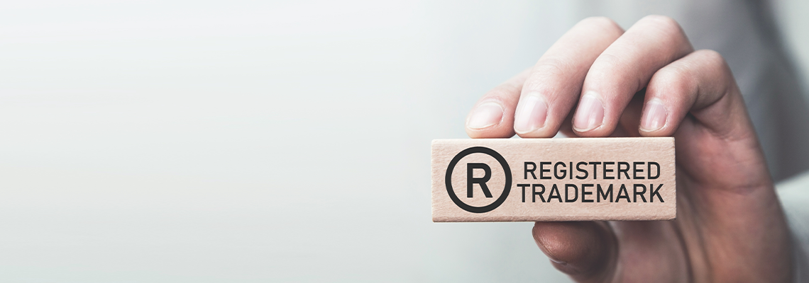 Male hand showing R-Registered trademark on wooden block