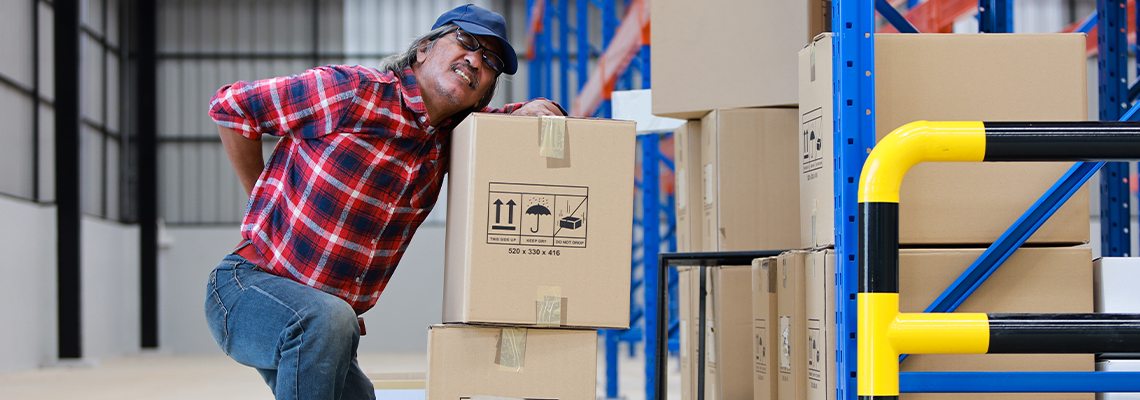 Asian worker man hurt his back .lift heavy box in factory