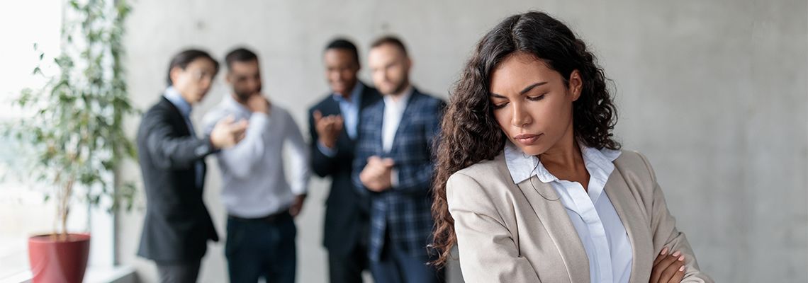 Male Colleagues whispering behind unhappy female