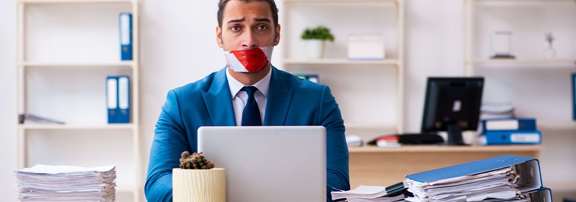 Employee with taped mouth working in office