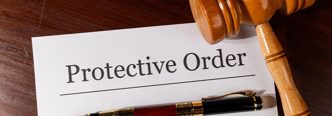 Protective Order Paper Set on Judge’s Desk with Gavel and Pen