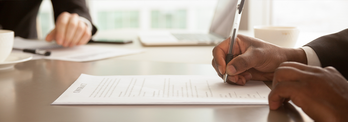 Horizontal closeup image black businessman sitting at desk signing contract