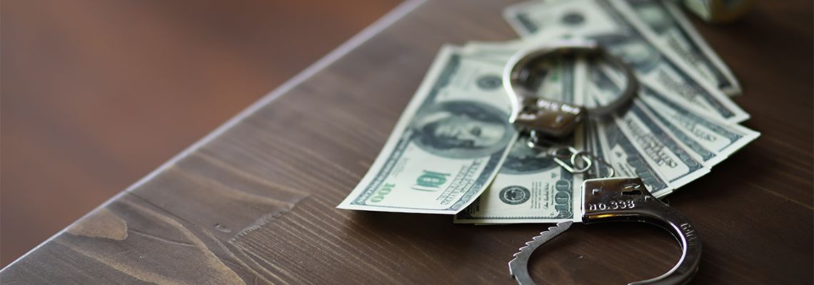 Handcuffs on Wooden Table with Dollar Bills