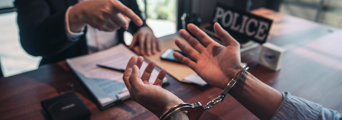 Police officer interrogating suspect or criminal man with handcuffs