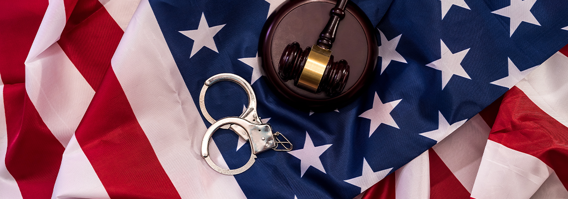 Judge gavel and handcuffs on american flag close up