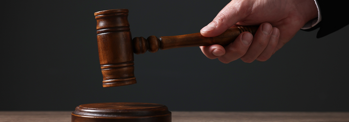Judge with gavel at wooden table against black background