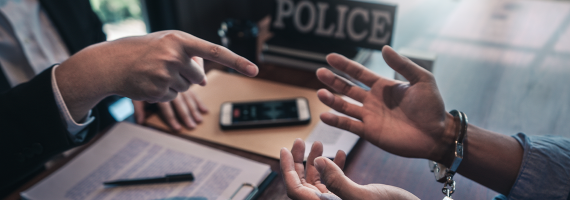 Police officer interrogating suspect or criminal man with handcuffs