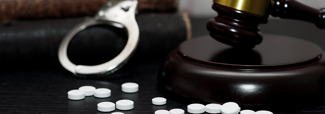 Judge's gavel with handcuffs, drugs on wooden table