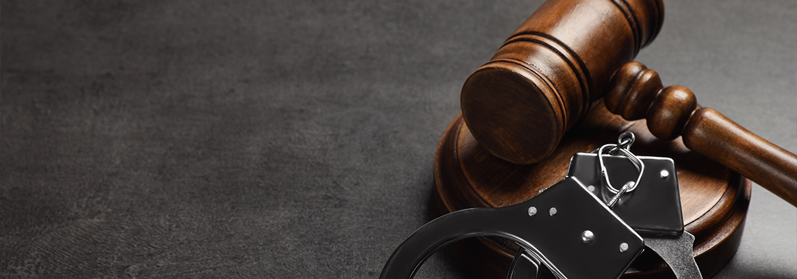Judge's gavel and handcuffs on grey background