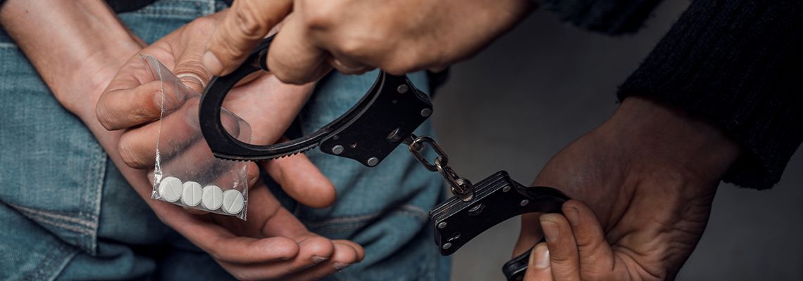 Police handcuffing man with drugs