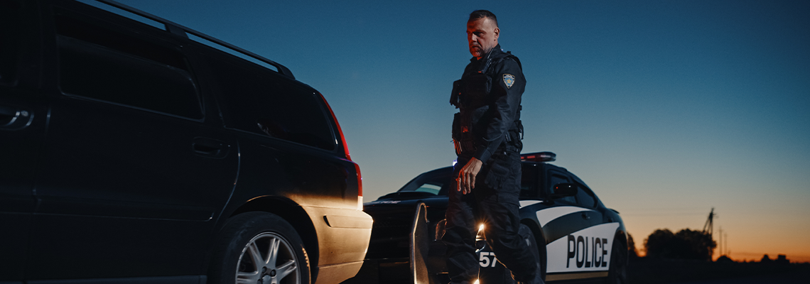 Cop Stepping out of a Police Car and Approaching a Pulled Over Car with Caution
