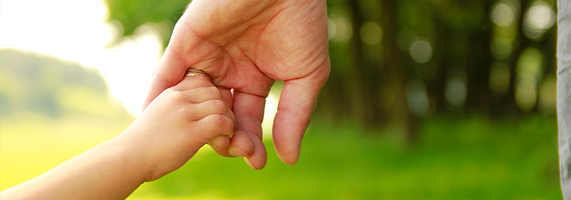 Parent holds the hand of a small child