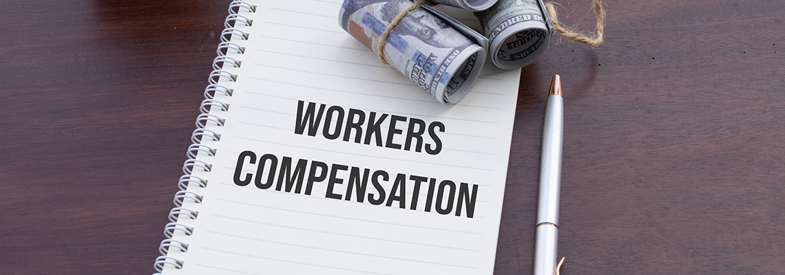 A notebook labeled 'Workers Compensation' accompanied by cash