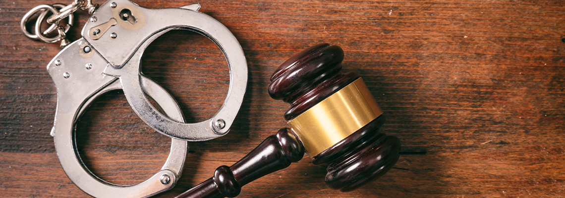 Handcuffs isolated and a gavel with copy space on a wooden background.