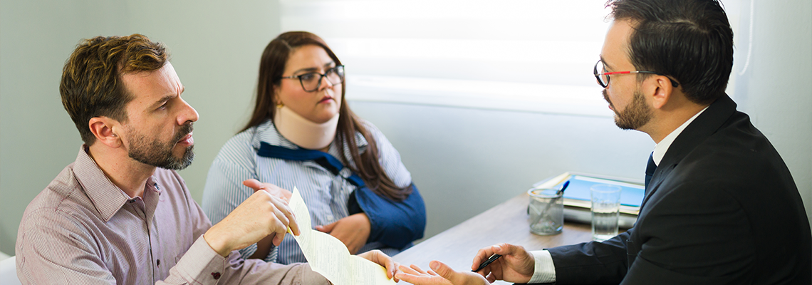 Clients discussing accident claim with lawyer in office