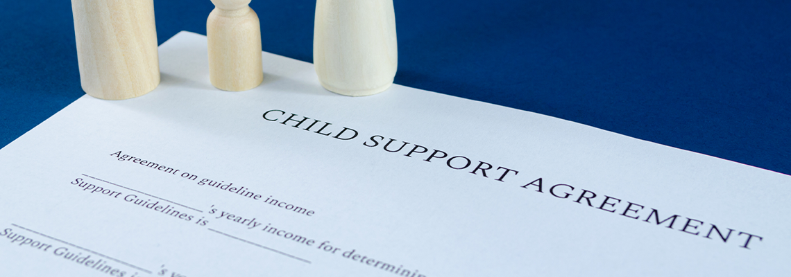 Printed child support agreement with man, woman and child wooden figures