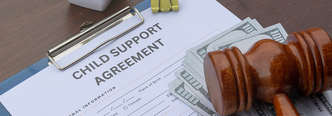 Child support agreement paper on a desk with cash, a gavel, and a calculator