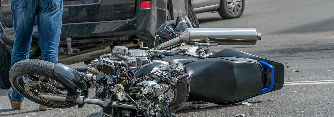 Broken motorcycle closeup beside the car. an accident on the road in the city