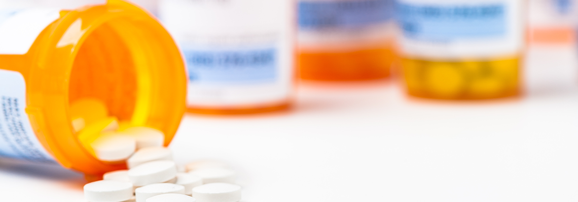 Round white prescription medication medicine pill tablets spilling from a bottle