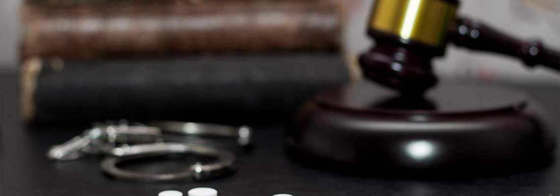 Judge's gavel with handcuffs, drugs on wooden table