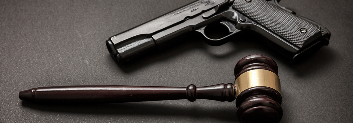 Judge gavel and a 9mm pistol on black background