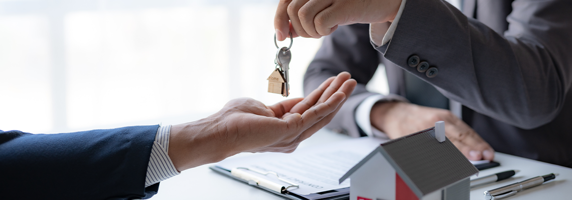 A professional real estate agent is giving house keys to a client during a property sale