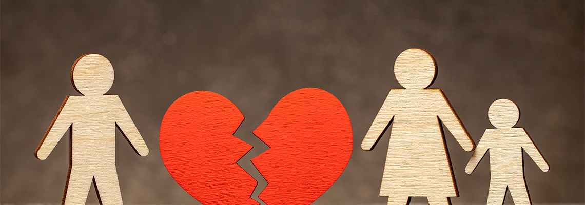 Wooden figures of a family divided, with a broken heart in the middle