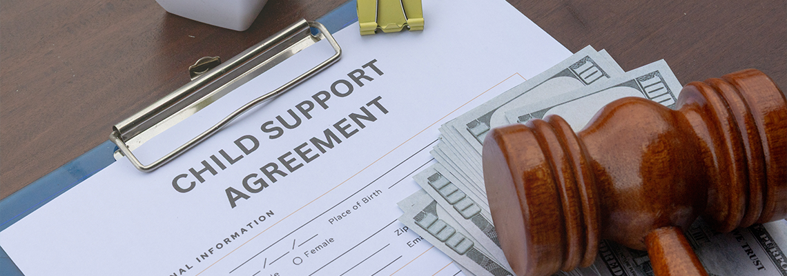 Child support agreement paper on a desk with cash, a gavel, and a calculator