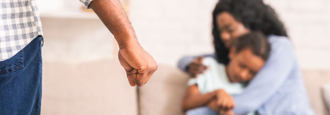 Closed fist of a man with scared mother and daughter in background