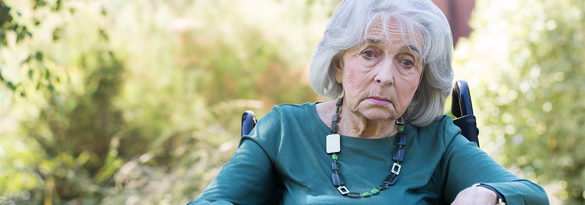 Depressed Senior Woman In Wheelchair Sitting Outdoors
