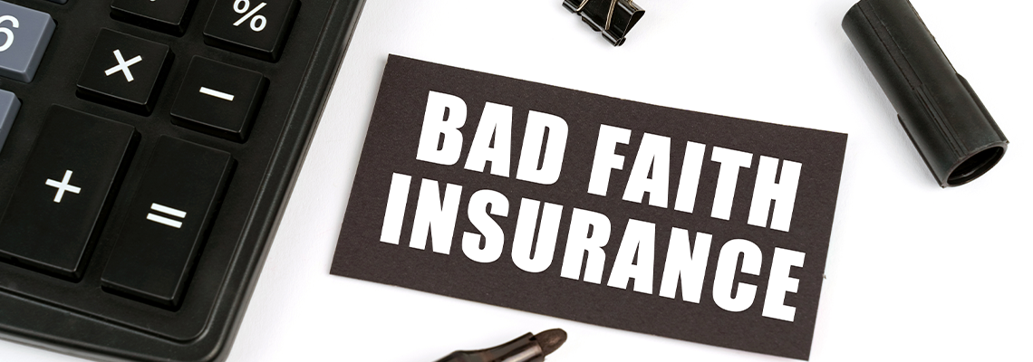 On a white table there is a calculator, a marker and a black plate with the inscription - Bad Faith Insurance