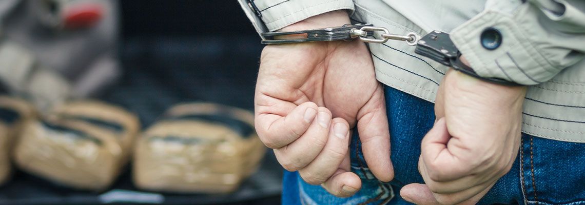 Handcuffed man with pouches of drugs
