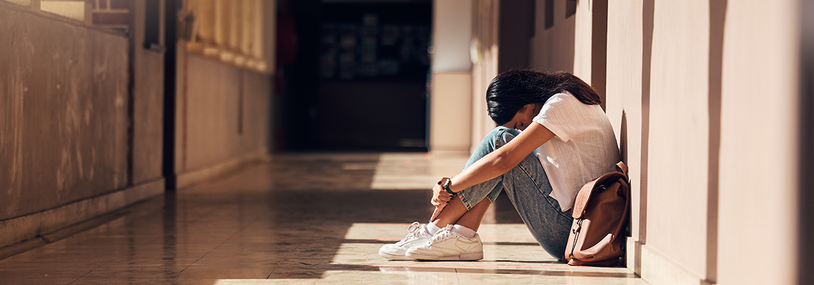 Sad, lonely and girl with depression at school, crying and anxiety