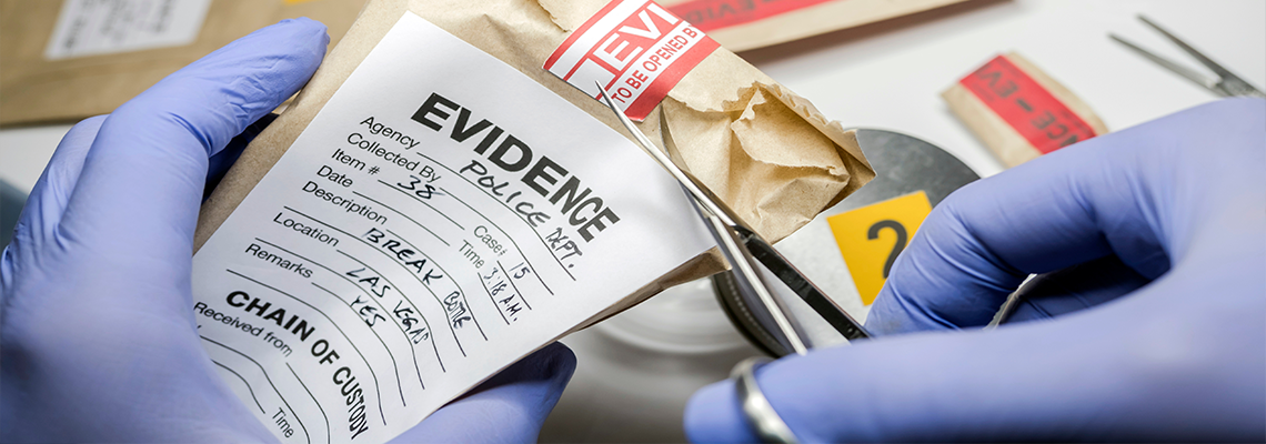 Gloved hands opening an envelope marked "evidence"