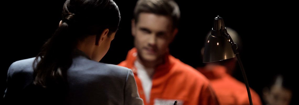 Person in suit sitting across from person in orange jumpsuit