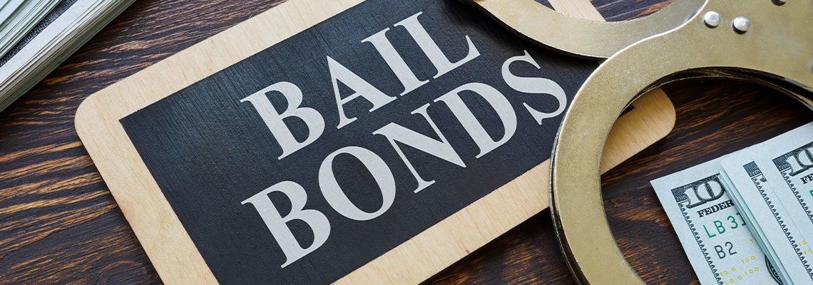 Word Bail Bond on blackboard with handcuff and dollar bill