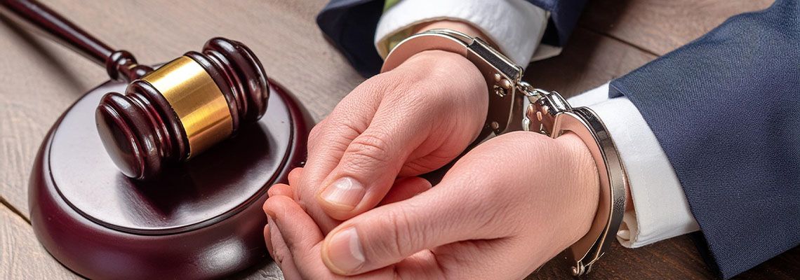 Handcuffed hands with gavel on table