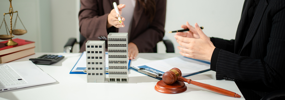 Real estate lawyer reviewing property contract with building model and gavel