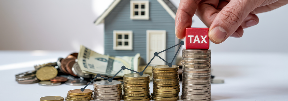 Hand Placing Tax Block on Stacked Coins with Model House and Money